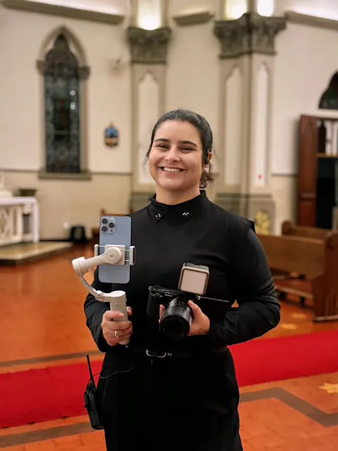 Gio Gabriel numa igreja, com o celular no estabilizador e a câmera nas mãos